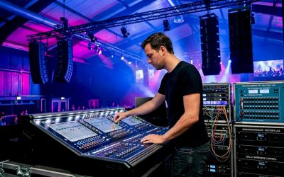 Een technicus stelt de geluidsvertraging van de luidsprekers in de zaal nauwkeurig af.