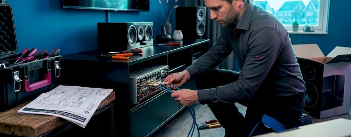 Man die bezig is om de kabels van zijn audiosysteem thuis aan te sluiten