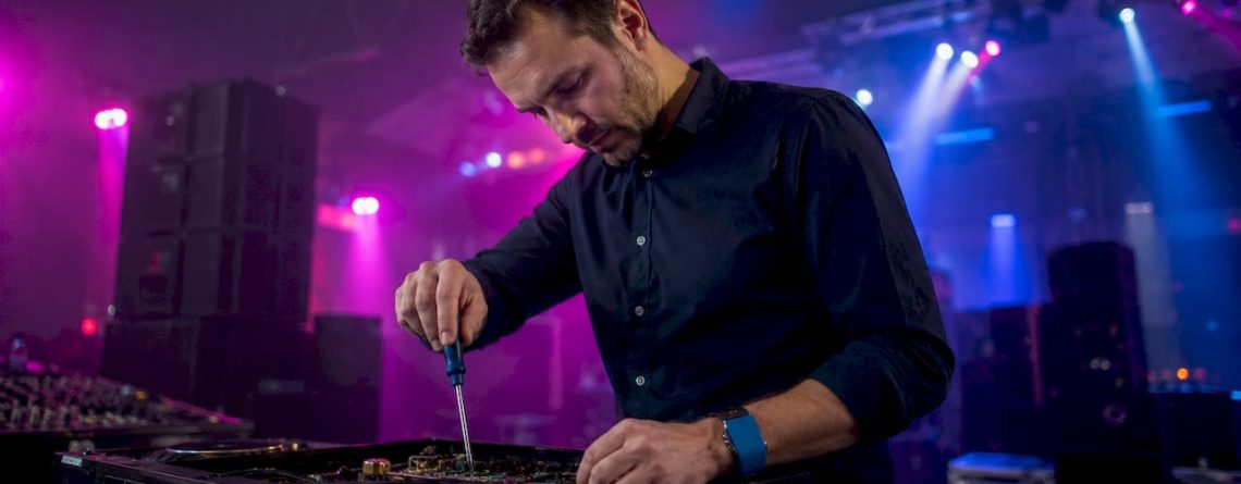 Een technicus controleert zorgvuldig een professionele audiomixer.