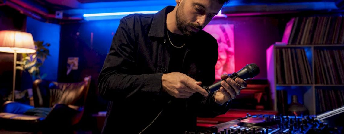 De DJ plugt zijn microfoon in op het mengpaneel.