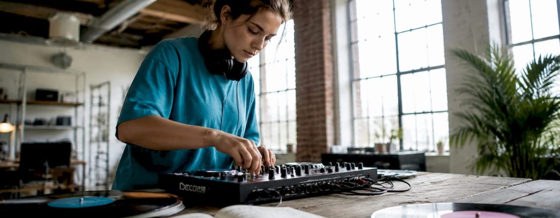 Een jonge vrouw is thuis enthousiast bezig met het instellen van haar eerste DJ-mixer.
