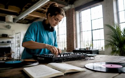 Een jonge vrouw is thuis enthousiast bezig met het instellen van haar eerste DJ-mixer.