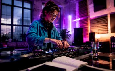 Een jonge dj draait aan de knoppen van zijn mengpaneel in zijn studio thuis.