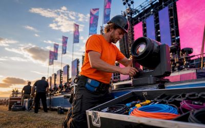 Een lichttechnicus hangt de verlichting op aan het podium van een festival.