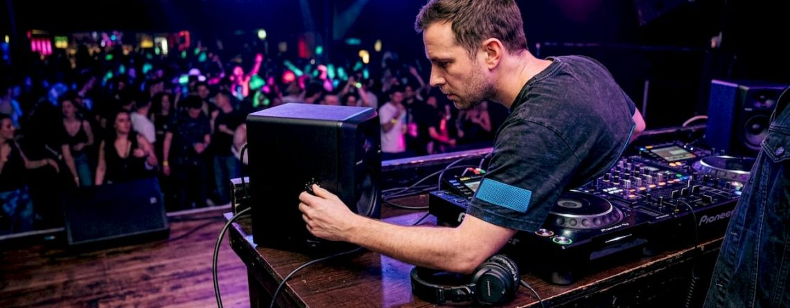 Een DJ stelt het geluid van de monitor in achter de draaitafels in een club.