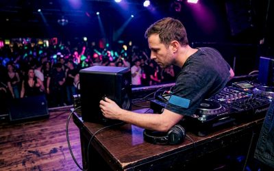 Een DJ stelt het geluid van de monitor in achter de draaitafels in een club.