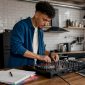 Een jonge man is thuis bezig met zijn dj-controller en draait muziek vanuit zijn eigen studiohoekje.