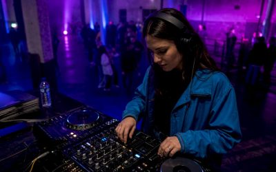 Een DJ staat met zijn koptelefoon op in de club en bereidt het volgende nummer voor.