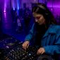 Een DJ staat met zijn koptelefoon op in de club en bereidt het volgende nummer voor.