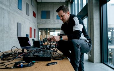 Een DJ is in zijn thuisstudio bezig met het netjes wegwerken en ordenen van alle kabels.