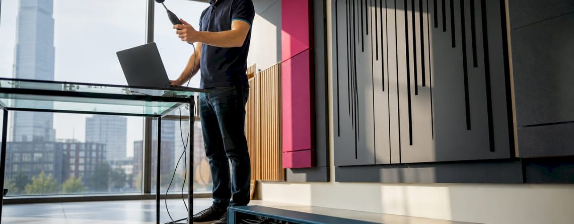Een technicus stelt de studiomonitors nauwkeurig af voor optimale geluidskwaliteit.