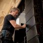 Een technicus is bezig met het installeren van een line array speakersysteem.