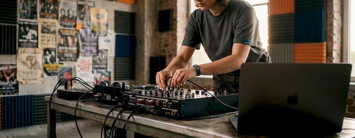 Een DJ is bezig met het aansluiten van kabels op zijn mengpaneel in zijn thuisstudio.