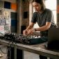 Een DJ is bezig met het aansluiten van kabels op zijn mengpaneel in zijn thuisstudio.