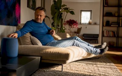 Een man zet muziek op in een woonkamer waar het geluid hol klinkt.
