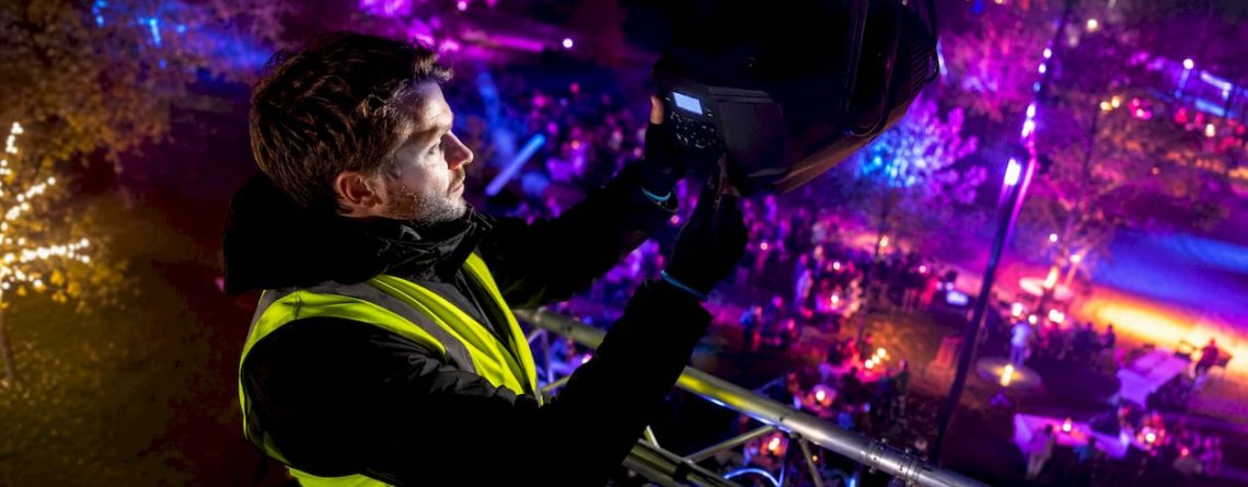 Een technicus is 's avonds tijdens een festival bezig om een LED-lamp af te stellen.