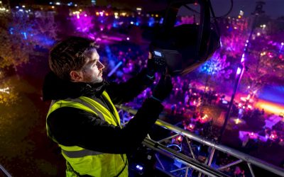 Een technicus is 's avonds tijdens een festival bezig om een LED-lamp af te stellen.