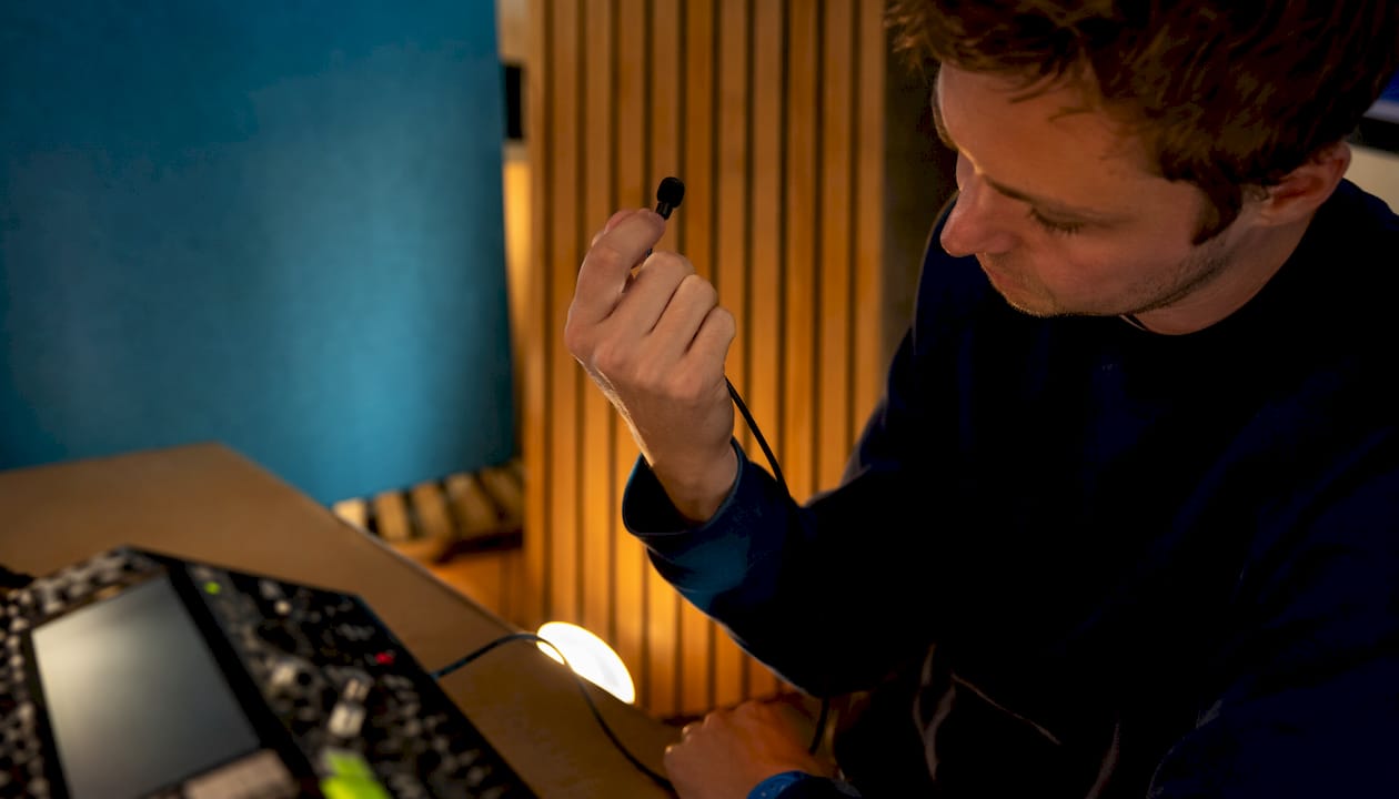 Een close-up van handen die een microfoon en een geluidsmeter vasthouden.