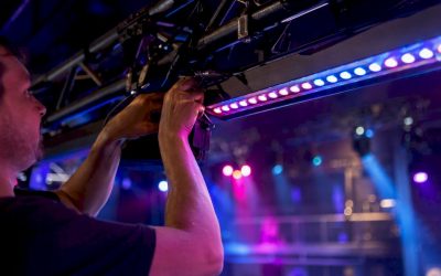 Een technicus bevestigt een LED-lichtbalk aan een trussconstructie.