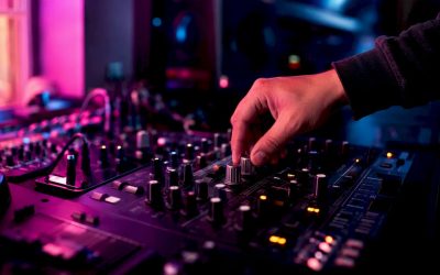 Een hand draait nauwkeurig aan de pan-knop van een DJ-mixer.