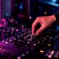 Een hand draait nauwkeurig aan de pan-knop van een DJ-mixer.