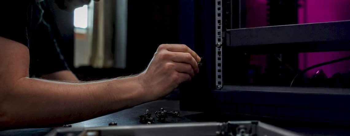Een technicus plaatst een kooimoer in een 19-inch serverrek.