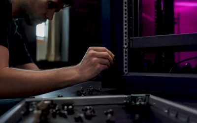 Een technicus plaatst een kooimoer in een 19-inch serverrek.