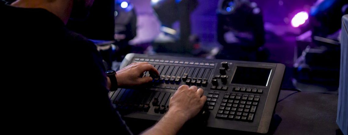 Backstage worden de schuifregelaars op de DMX-controller nauwkeurig afgesteld door handen die zorgen voor de perfecte lichtsfeer.