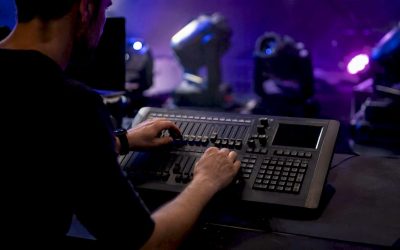 Backstage worden de schuifregelaars op de DMX-controller nauwkeurig afgesteld door handen die zorgen voor de perfecte lichtsfeer.