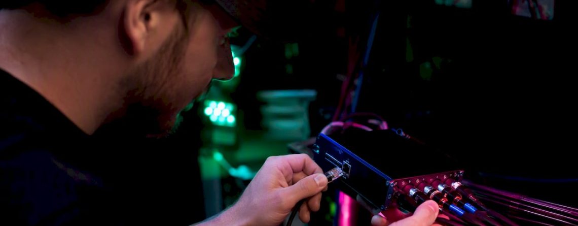 Een technicus sluit een ethernetkabel aan op een DMX-node.