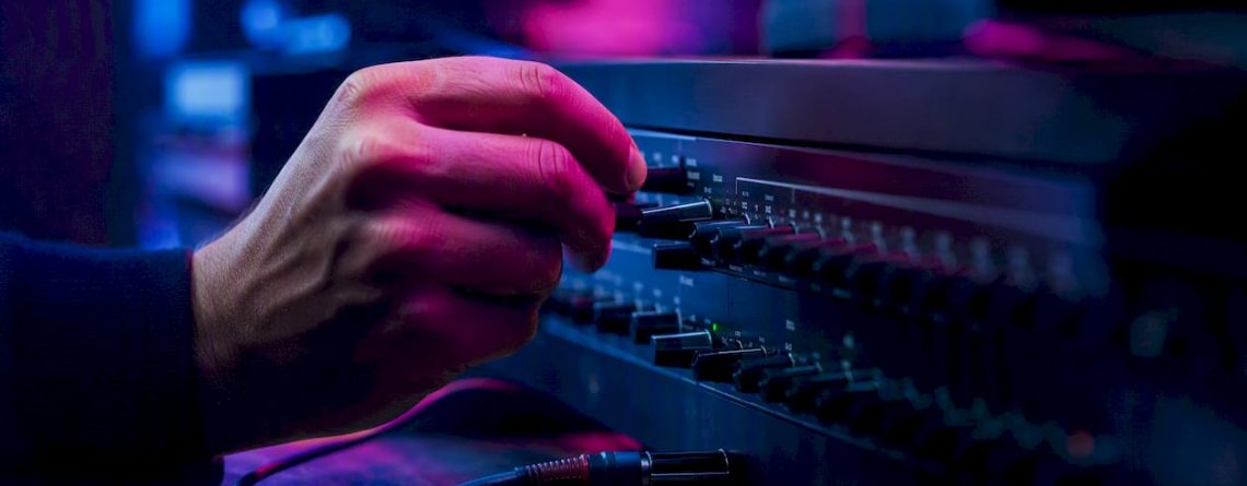 Een DJ draait aan de knoppen van de audiomixer om het geluid perfect af te stemmen.