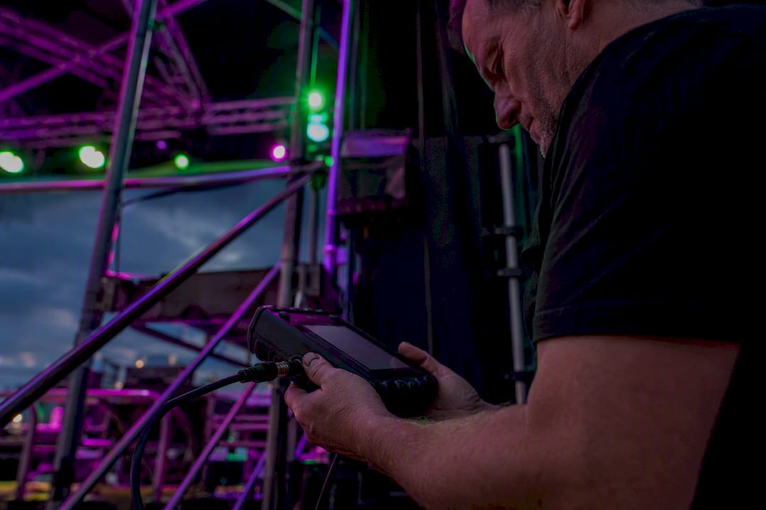 Een technicus test de podiuminstallatie met een RDM-tester.
