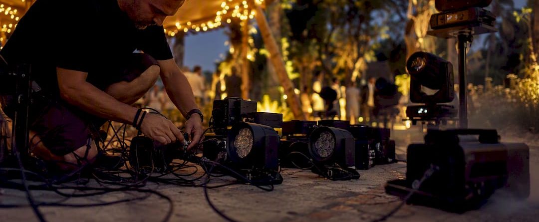 Een technicus is bezig met het installeren van uplights en bewegende spotlights.