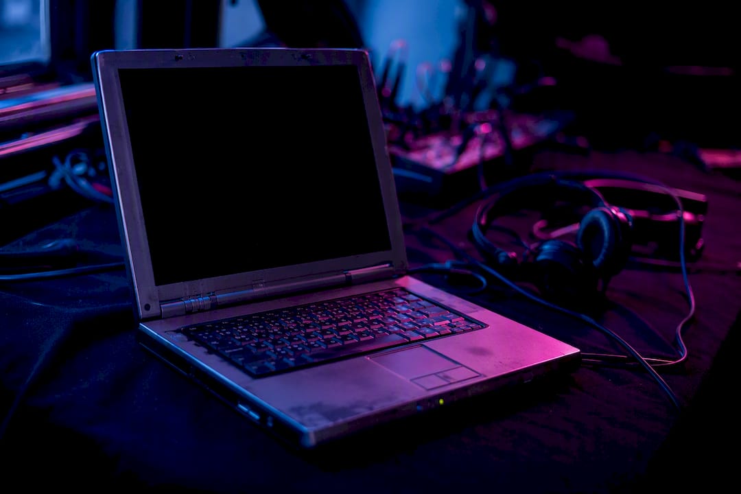 Close-up van een oudere laptop en dj-kabels in sfeerverlichting