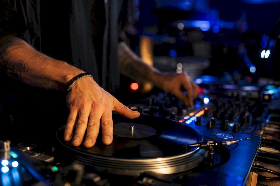 Handen die scratchen op een vinyl draaitafel in gedempt licht