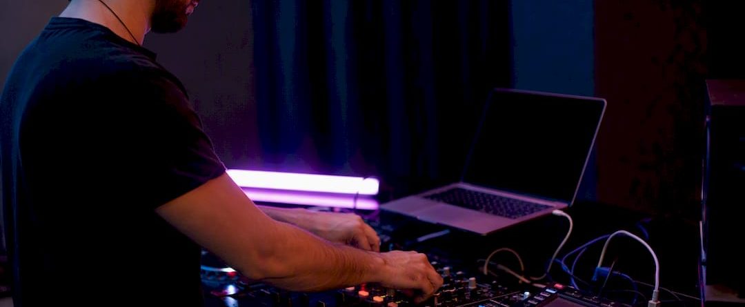 Handen van een dj die de mixer en koptelefoon afstellen in een donkere werkruimte