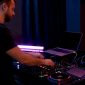 Handen van een dj die de mixer en koptelefoon afstellen in een donkere werkruimte