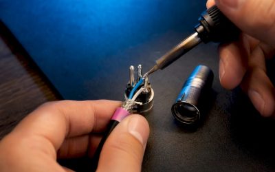 Handen die draden aan een XLR-connector solderen