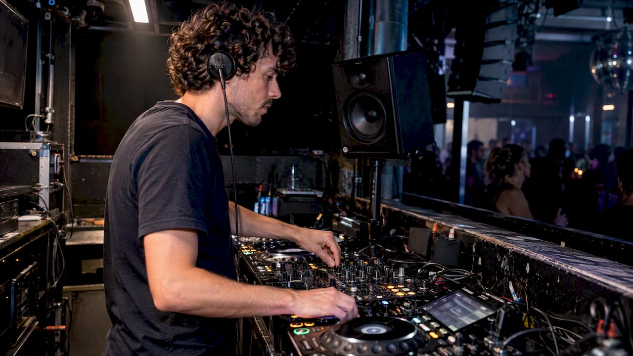 Dj luistert via de boothmonitor op oorhoogte